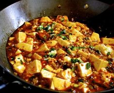 a pan filled with tofu and vegetables cooking on top of a stovetop oven