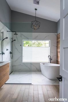 a large bathroom with marble walls and flooring, including a bathtub in the center