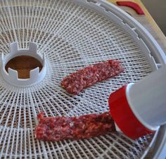 two pieces of meat sitting on top of a white mesh tray with red plastic cups