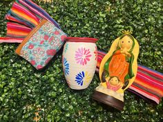 three colorful vases sitting on top of a lush green field next to each other