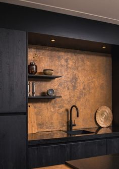 a kitchen with black counter tops and wooden shelves on the wall, along with a sink