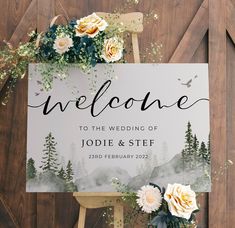 a welcome sign with flowers and greenery on it