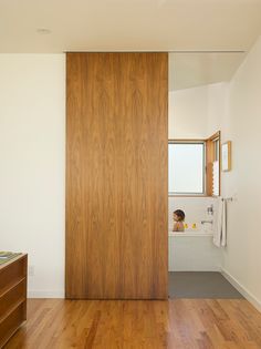 a bathroom with wood flooring and a white bathtub next to a wooden door