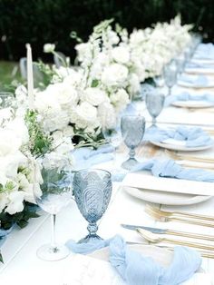 the table is set with white flowers and blue napkins