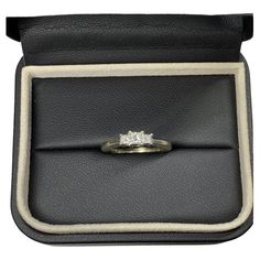 an engagement ring in a black leather case with white stitching around the band and center stone