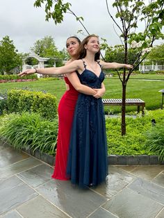 two women in long dresses standing next to each other with their arms around one another