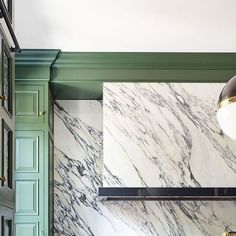 a kitchen with green cabinets and marble counter tops, along with an oven in the center