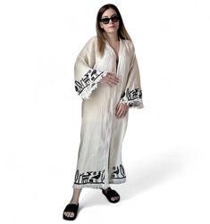 The Hittite printed  muslin kimono combines elegance and comfort seamlessly. Made from organic cotton, it offers an eco-friendly choice, while the OEKO-TEX certification ensures its health and environmental consciousness.  The kimono will elevate every moment with its sophistication, featuring unique patterns created using traditional woodblock printing and natural dyes. Suitable for both casual and special occasions, it effortlessly complements various outfits, adding a touch of style to your l Traditional Kimono For Spring Beach Cover-up, Long Beige Kimono For Festival, Beige Long Kimono For Festival, White Long-sleeve Kaftan With Woven Motifs, White Long Sleeve Kaftan With Woven Motifs, White Bohemian Maxi Kimono, White Bohemian Maxi Length Kimono, Traditional Printed Maxi Kimono, Traditional Maxi Length Printed Kimono