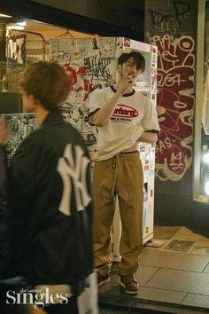 a man standing next to a refrigerator covered in graffiti