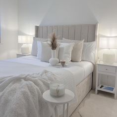 a bed with white linens and pillows in a bedroom next to two nightstands