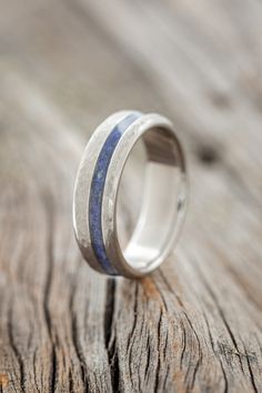 a silver ring with blue and white wood inlays on the outside of it