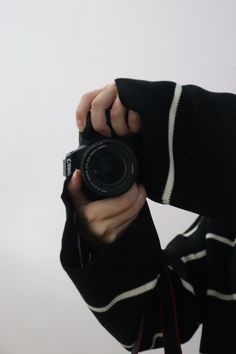 a person holding a camera up to their face with one hand and the other in front of them