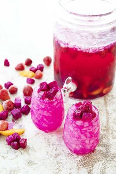 raspberry lemonade punch in two glasses next to a jar filled with fruit