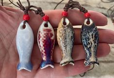 three fish shaped pendants are being held in someone's hand