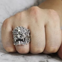 a person's hand with a silver ring on their finger and an animal head in the middle