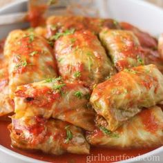 stuffed cabbage rolls with marinara sauce and parsley on top in a white bowl