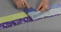 a person is cutting fabric with scissors on a piece of cloth that has been sewn together