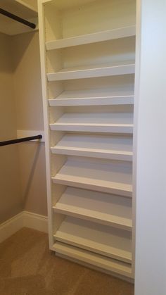 an empty walk in closet with white shelving