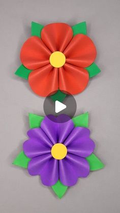 three different colored flowers on a gray surface with one red and one purple flower in the center