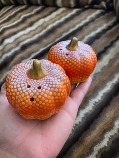 two orange painted pumpkins sitting on someone's hand