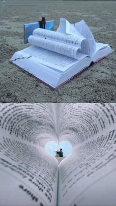 an open book laying on top of a sandy beach next to a heart shaped hole