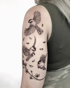 a woman's arm with birds flying around it and leaves coming out of the back