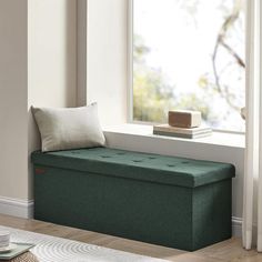 a green bench sitting in front of a window next to a cup and saucer