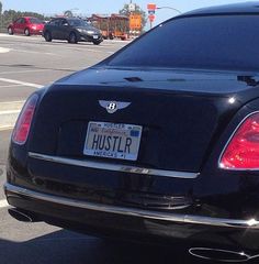 the back end of a black bentley parked at an intersection