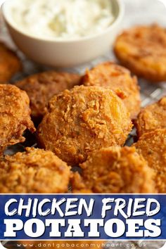 some fried food is sitting on a cooling rack next to a bowl of ranch dressing