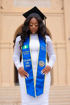 a woman wearing a blue and yellow graduation gown with her hands on her hips, standing in front of steps