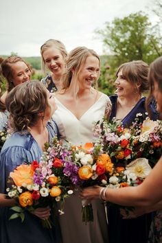 a group of women standing next to each other holding bouquets and smiling at each other