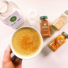 a person holding a cup of coffee next to some spices