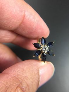 a person is holding a ring with blue and white stones in it's middle