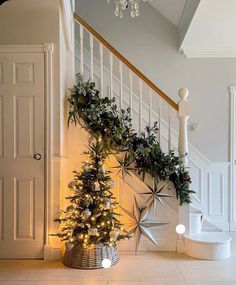 a decorated christmas tree sitting under a stair case next to a banister with lights on it