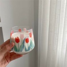 a hand holding a glass with flowers painted on it