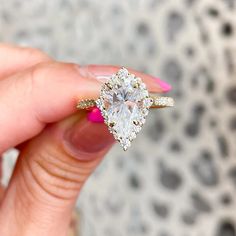 a woman's hand holding an engagement ring with two pear shaped diamonds on it