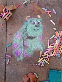 a child's feet standing next to a sidewalk with colored crayons on it