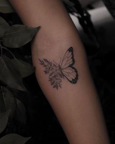 a black and white butterfly tattoo on the right arm, with leaves in the background