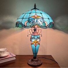 a lamp that is sitting on top of a table next to a cup and saucer