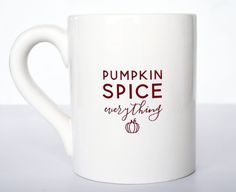 a white coffee mug with the words pumpkin spice next to it on a white surface