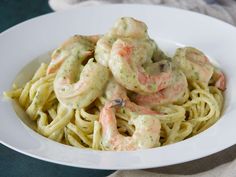 pasta with shrimp and cream sauce in a white bowl on top of a table cloth