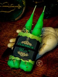 two green candles sitting on top of a wooden table