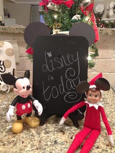 an elf and mickey mouse are standing next to a sign