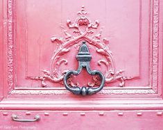 a pink door with a metal handle on it's side and ornate carvings around the top