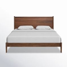 a bed with white sheets and wooden headboard