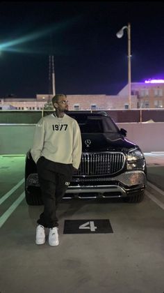 a man standing next to a car in a parking lot