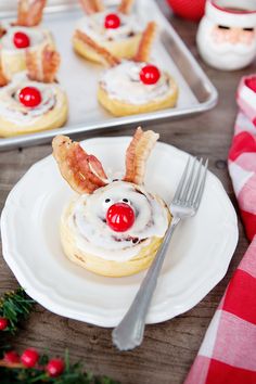 a plate with some food on it next to a fork and cupcakes in the shape of santa's face