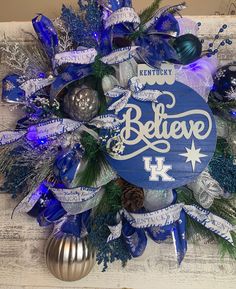 a christmas wreath with blue and silver decorations on it that says, believe 1 kentucky