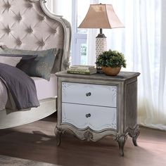 a bedroom with a bed, night stand and lamp on the side table in front of it