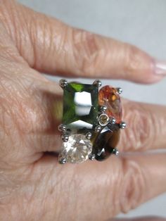 Stunning vintage 80's ring, new old stock. This is unique in as it's adjustable from about a size 6 1/2 to about a size 8 1/2, from inside the ring so you don't see it. Elegant faux stones with amazing earthy colors. You have yellows, greens, browns, and clear. Looks so rich! Measurements are about 15mm long by 20mm wide. Set in a pretty silver tone setting for a little added elegance. You will enjoy this for years to come. Silver Emerald Ring, Vintage Silver Rings, Blowout Sale, Faux Stone, Earthy Colors, Multi Stone Ring, Favorite Rings, Multi Stone, Art Deco Style